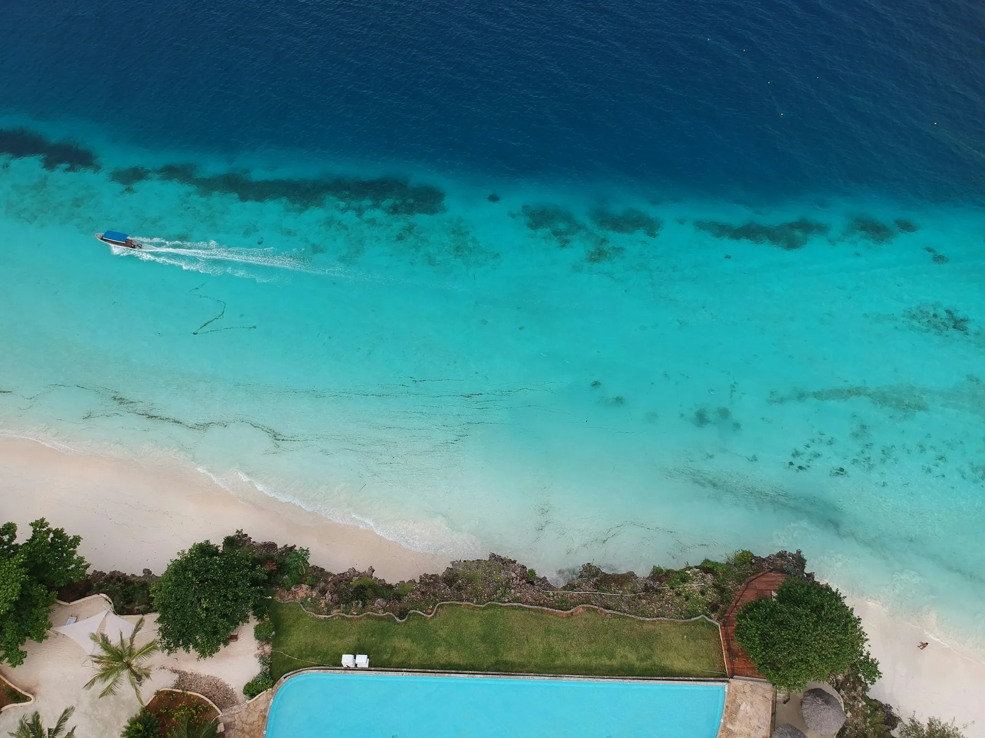 An aerial view of white sand and turquoise waters on the Zanzibar coast